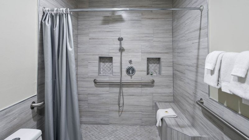 A bathroom shower with tiled walls, a grab bar, and a shower curtain.