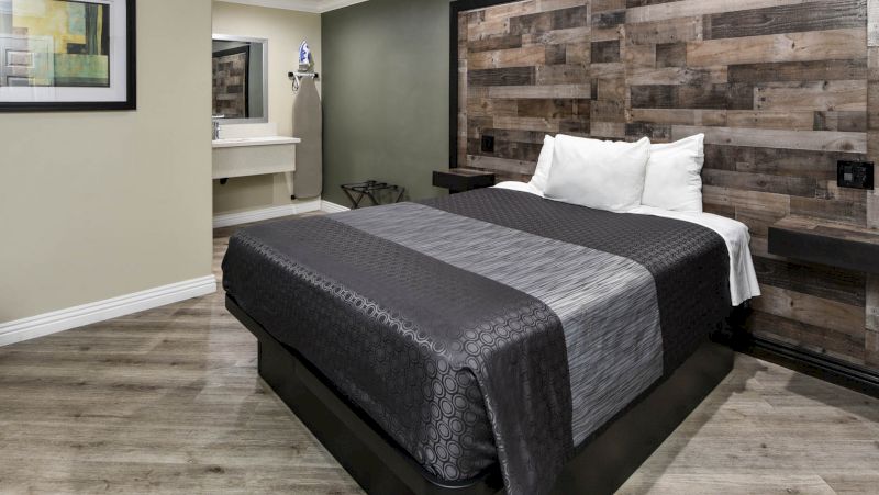 A hotel room with a large bed, wooden headboard, and a bathroom in the background.