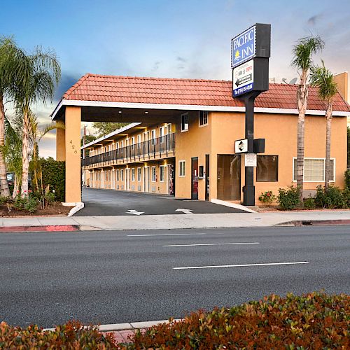 This image shows a roadside motel with palm trees, a sign displaying 