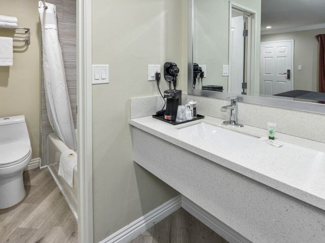 A clean bathroom with a sink, toilet, shower, and mirror
