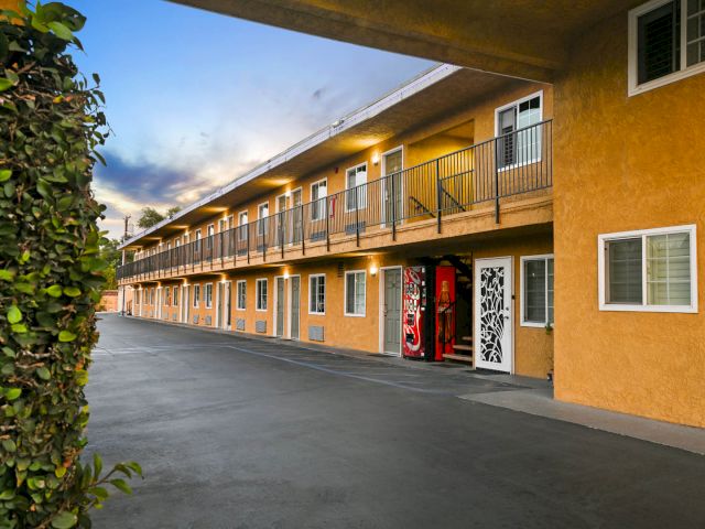 A two-story yellow building with balconies and a parking lot.