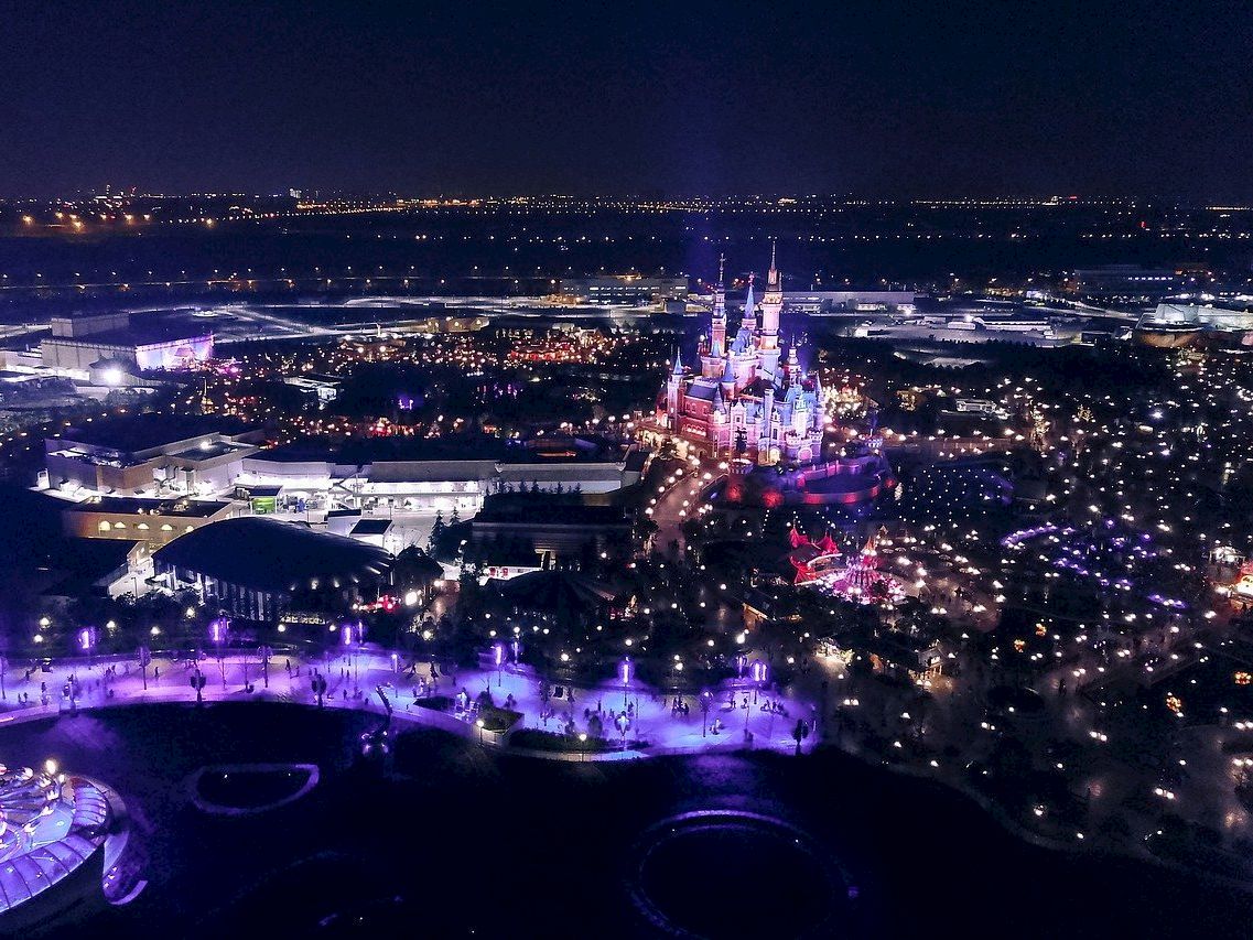 A nighttime aerial view of a lit-up castle in a city.