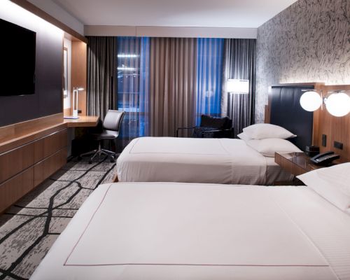 A hotel room with two beds, a desk, and a TV.
