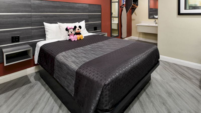 A hotel room with a bed, nightstand, and sink