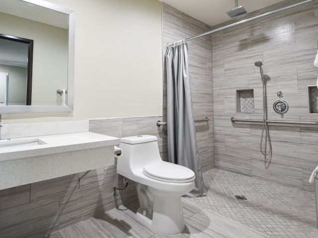 A clean bathroom with a toilet, shower, sink, and mirror